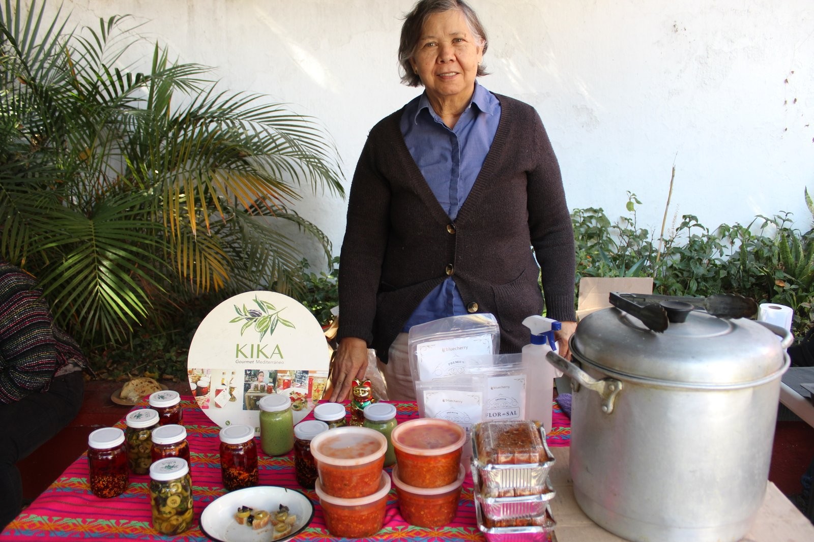 Responsable de Kika Gourmet Mediterráneo en su puesto, junto al letrero de la marca y los frascos de conservas