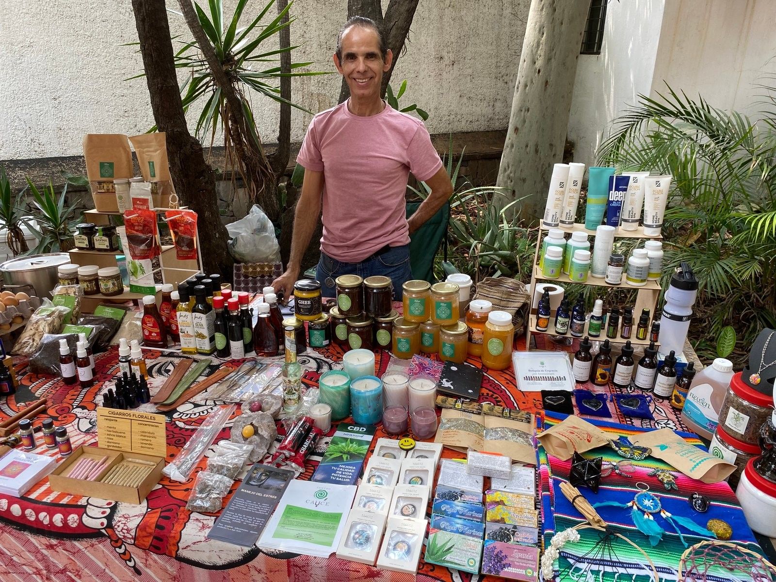 Vendedor de Corazón del Desierto en su puesto, con velas, miel, productos de spa y cajas de cigarros florales