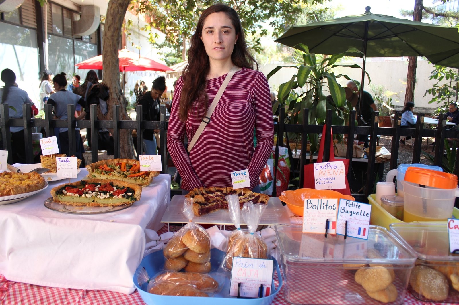 Responsable de Bel Ami en su puesto, con tartes, bollitos y pain de caja etiquetados en francés y español