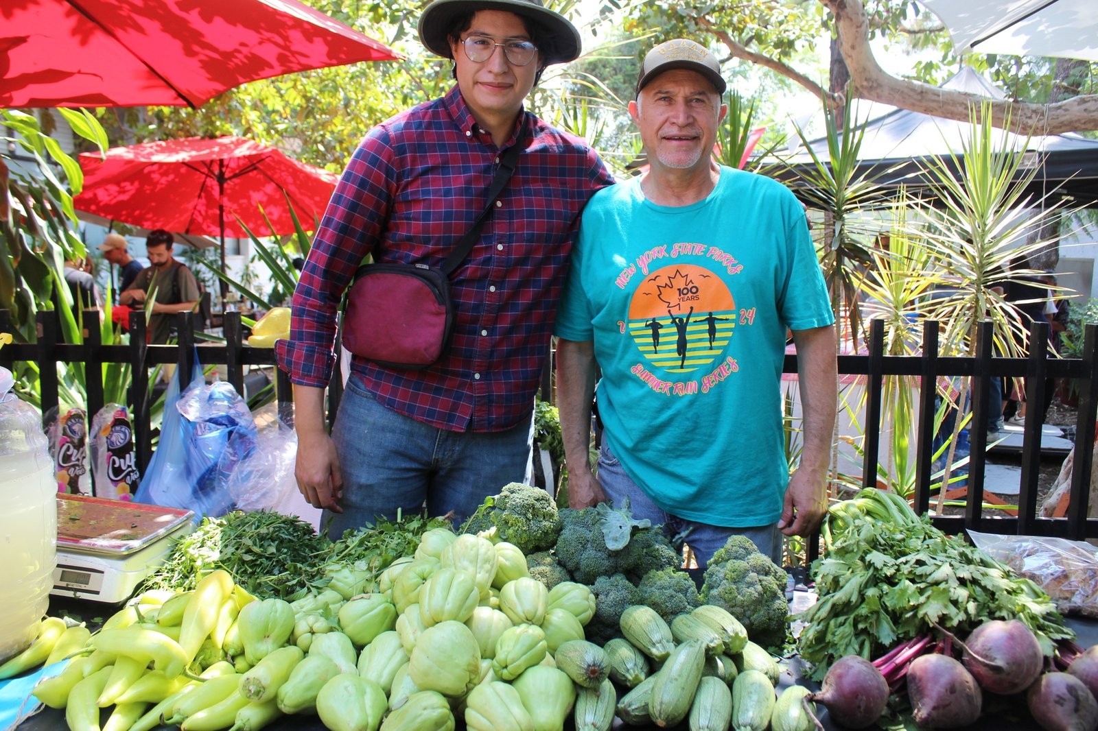 Dos productores de Ecoseda detrás de su mesa de chayotes, brócoli, calabacitas y betabeles