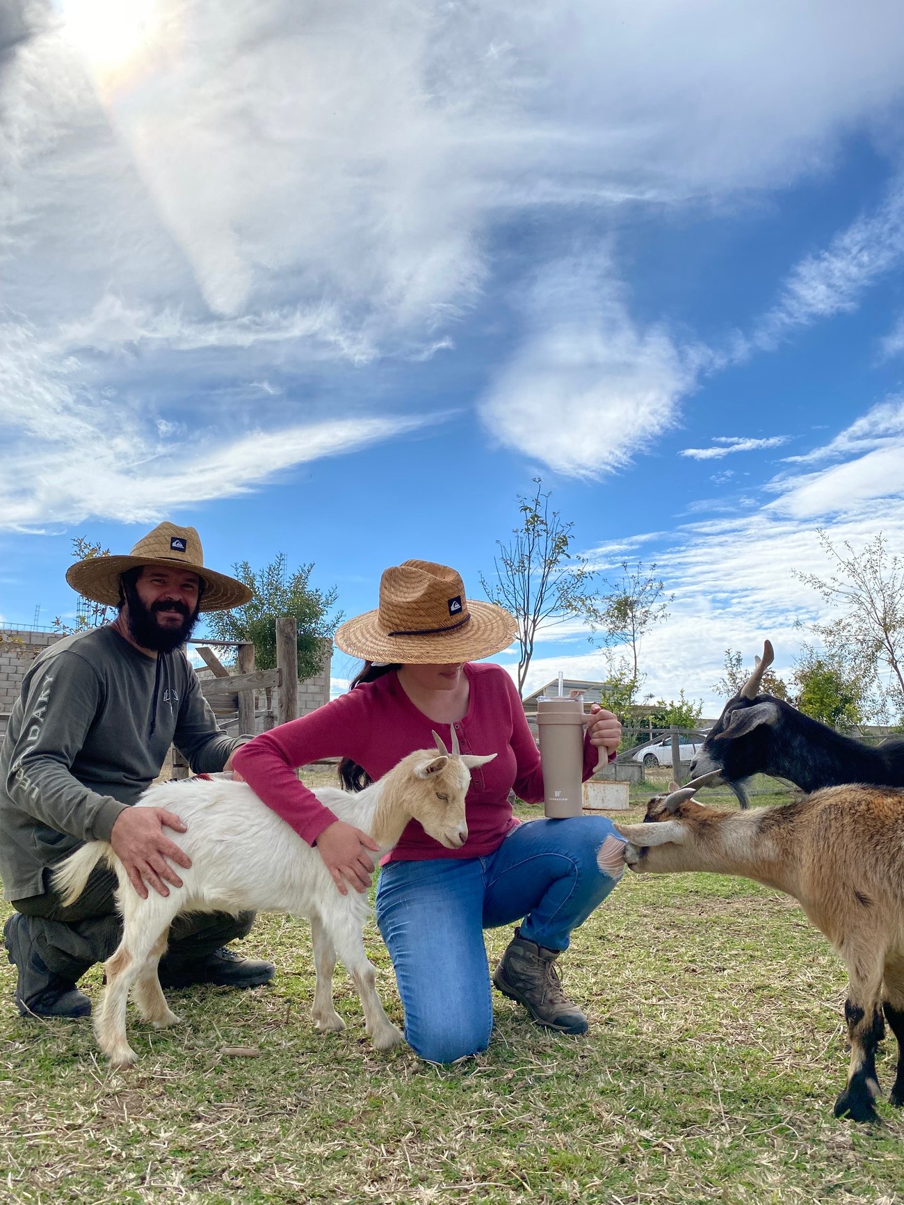 Los dos productores de Granja La Trigueña, con sombreros de paja, conviviendo con sus cabras en el rancho