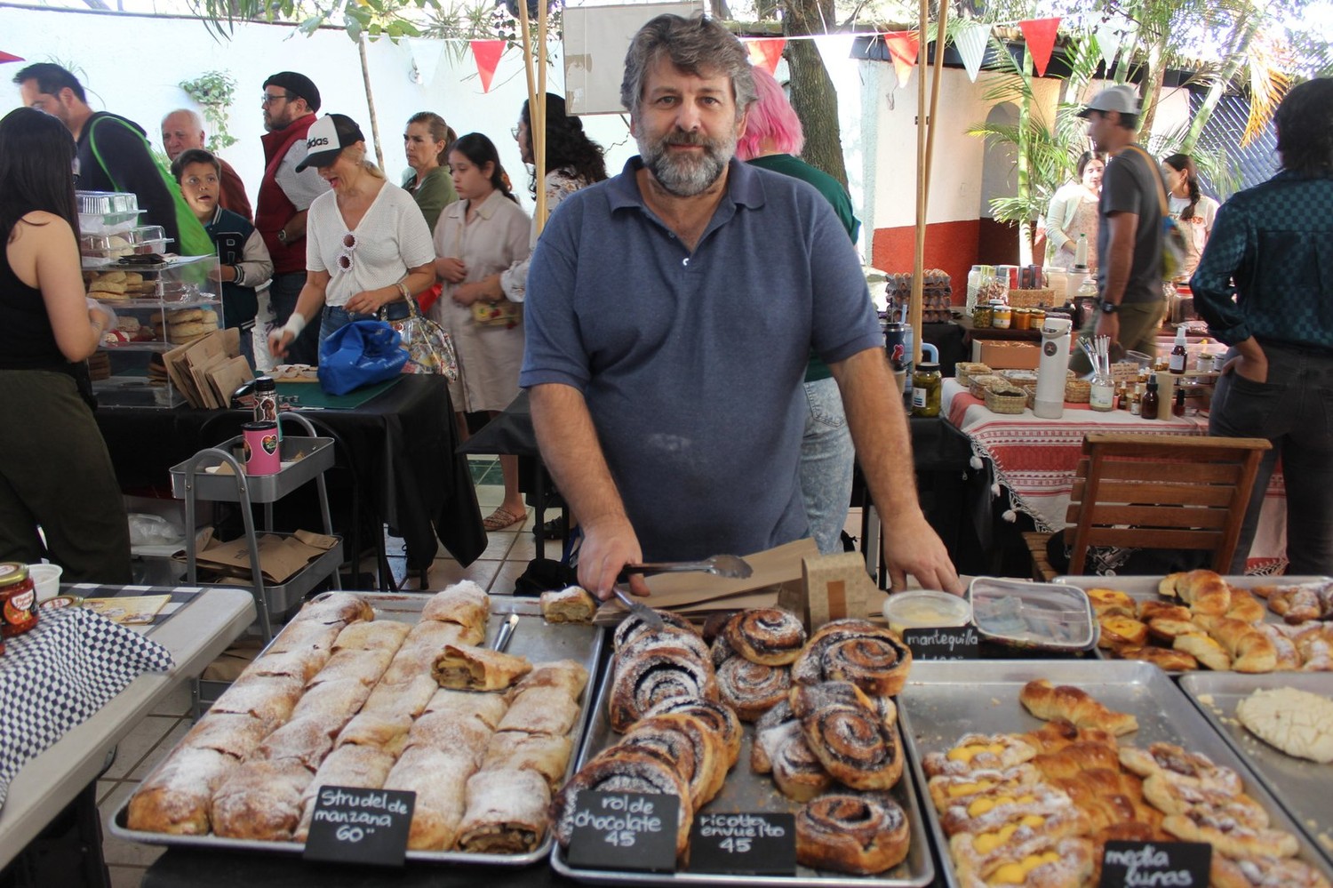 Vista amplia del puesto de La Empanadería, con el panadero sirviendo entre visitantes de la Feria