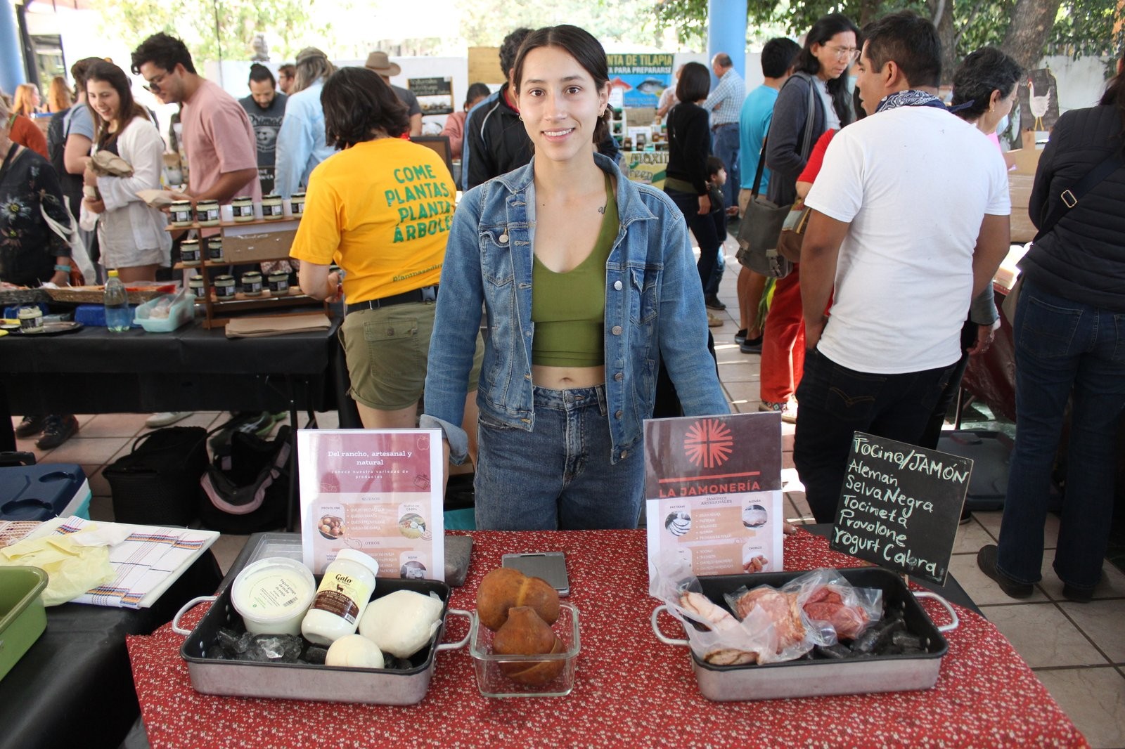 Krystal Polino en el puesto de La Jamonería, con charolas de jamones, tocino, queso de cabra y pan