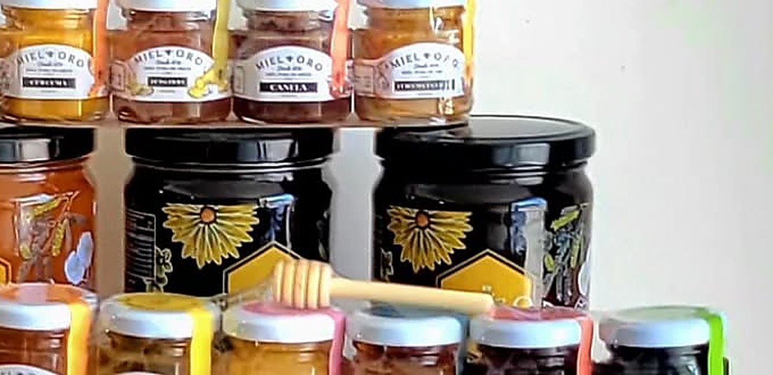 Hilera de frascos de miel varietal de Miel Oro con un dipper de madera para servir