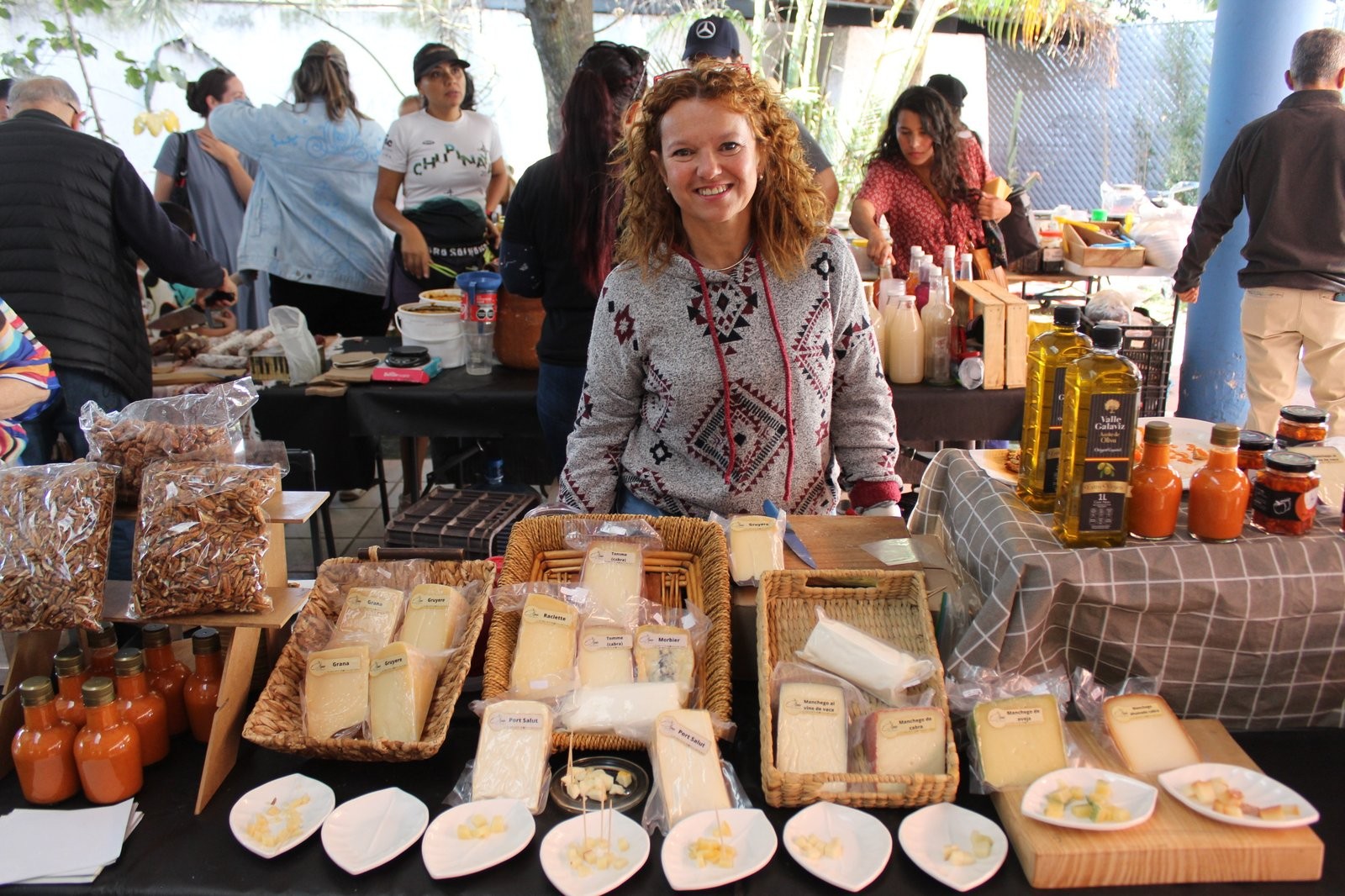 Una de las responsables de Olmo del Duero en el puesto, rodeada de canastas de queso, nueces, aceite de oliva y botellas de salsa
