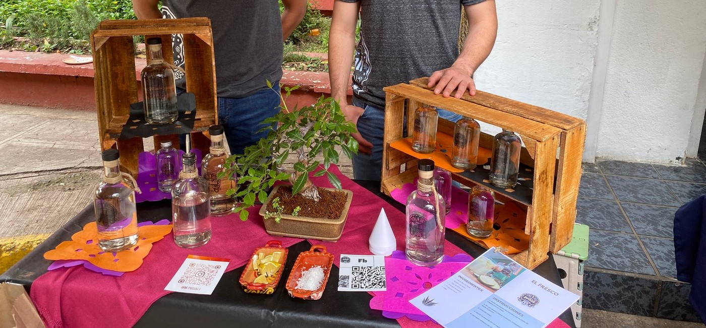 Botellas de Peuali sobre huacales de madera, con limón, sal y tarjetas de receta de cóctel