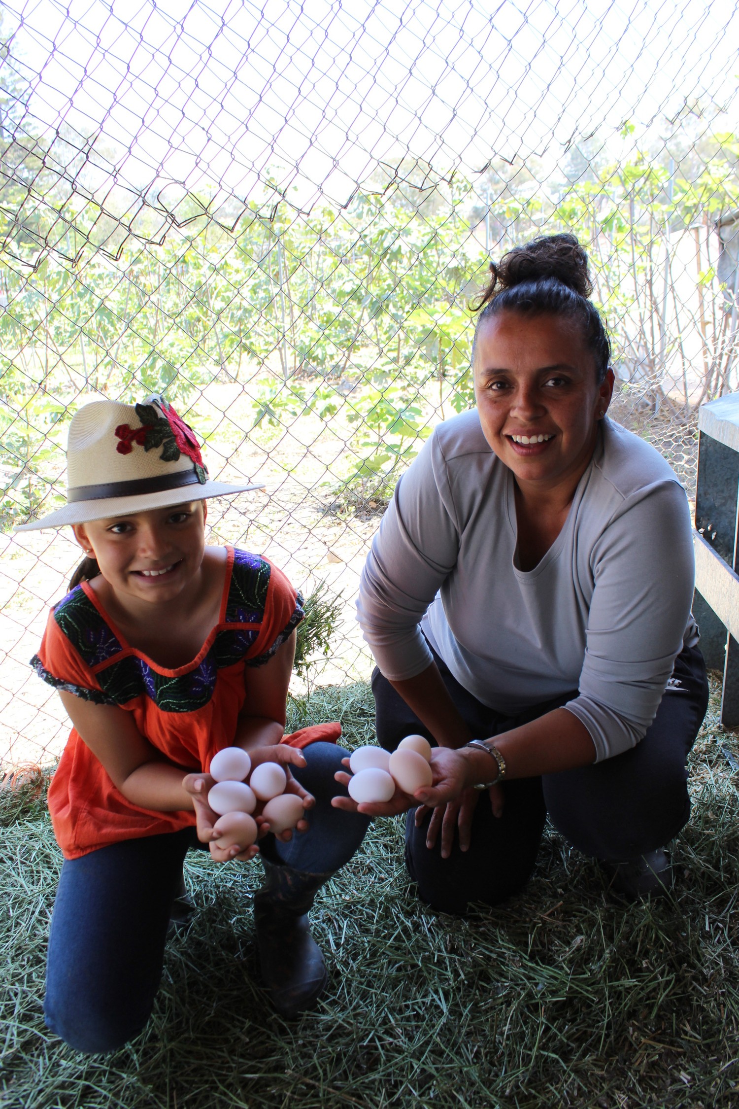 Madre e hija mostrando huevo fresco recién recolectado en el gallinero