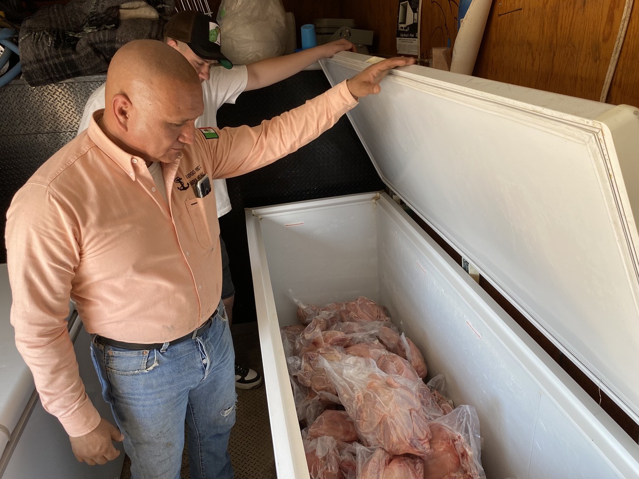 Dos integrantes de Rooster King revisando un congelador lleno de pollo empacado