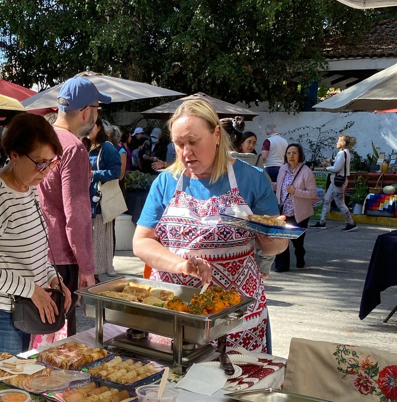 Cocinera de Varenky & Co. con mandil bordado tradicional eslavo sirviendo comida preparada