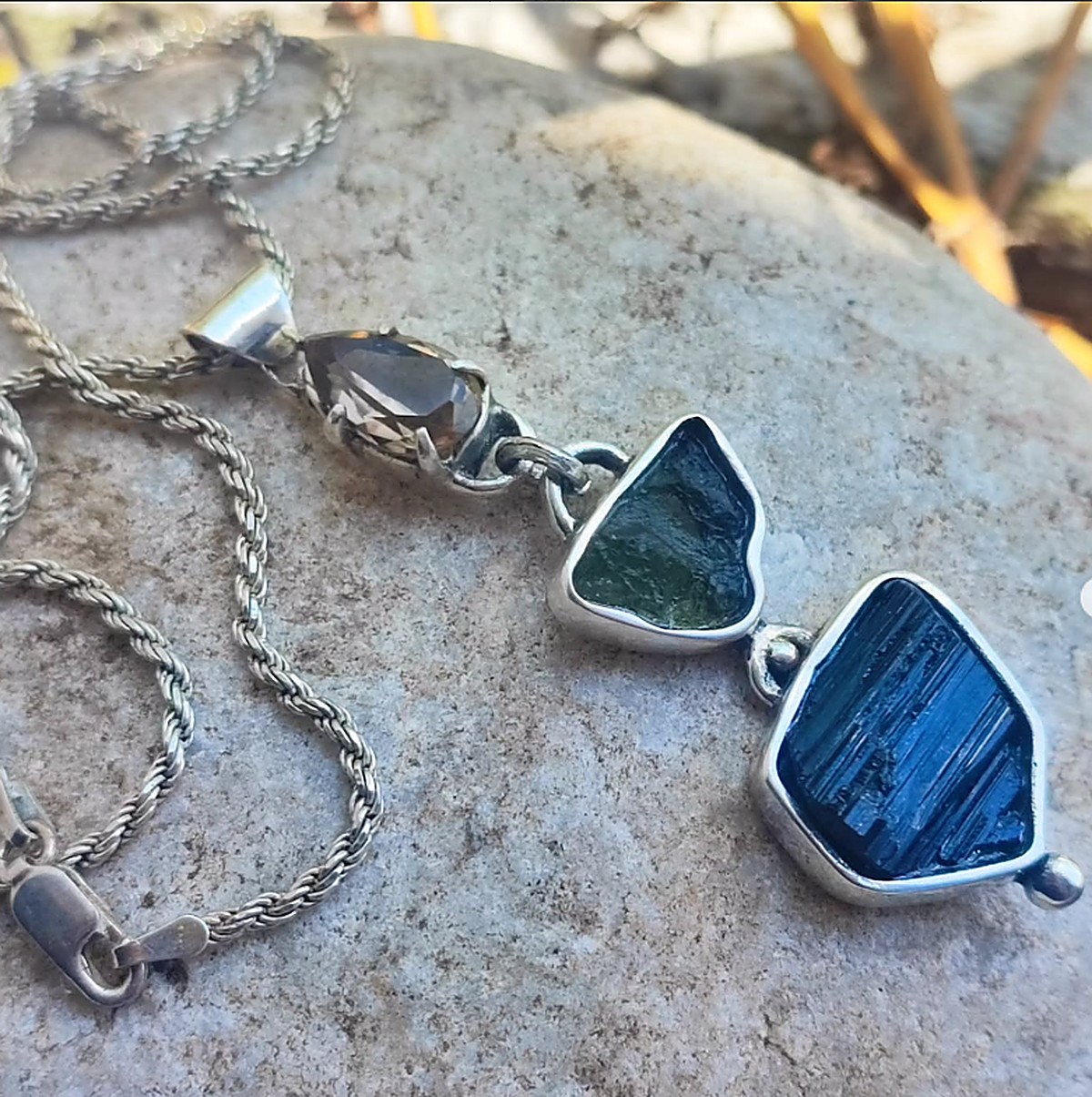 Collar de plata con cuarzo ahumado, turmalina verde y turmalina azul en bruto, sobre una piedra
